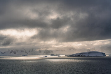 Epic Antarctica Frozen Landscape Sun on Ocean. Fine Art Photography. Sunlight Shines Through Clouds to Illuminate Seas and Islands.