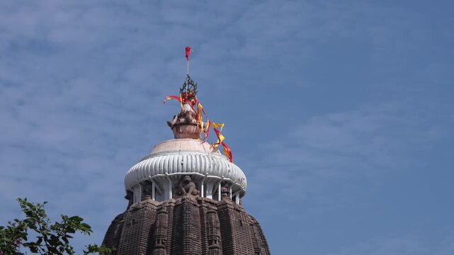 Close up of Jagannath Temple shikhara with sacred flag against blue sky, Puri, India