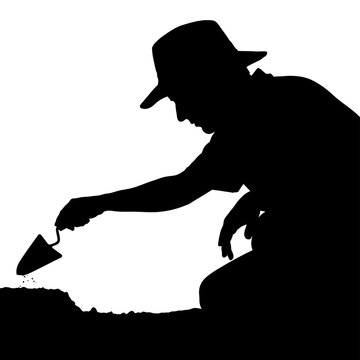 Silhouette of an archaeologist carefully excavating a historical site with trowel.