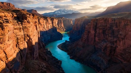 Vibrant turquoise river flows through a grand red rock canyon, bathed in the golden light of sunset, with distant snow-capped mountains beneath a dramatic sky