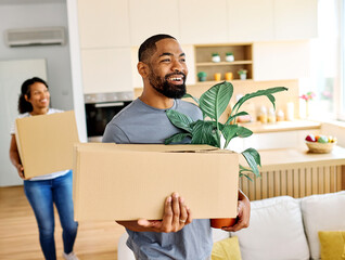 Young black couple moving into a new modern house, carrying boxes and arriving home together....