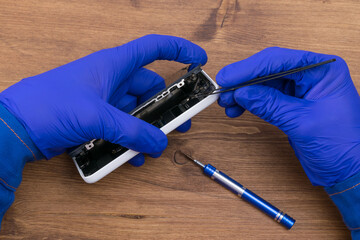 Hands of a craftsman repairing a broken phone display