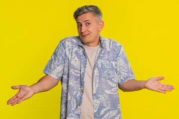 Middle-aged man shrugging shoulders and raising hands with uncertain look expressing confusion and...