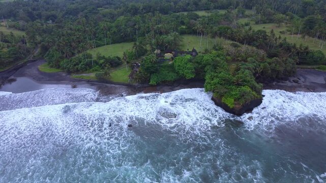 The Hindu temple of Pura Dalem from a bird's-eye view. The temple is located on Pantai Bonian Beach, which has volcanic black sand, in the Indian Ocean on the island of Bali. Dron. 4К