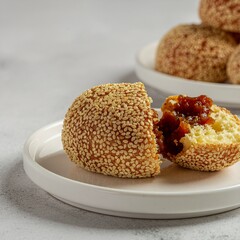 High-quality photo of traditional Indonesian onde-onde, whole and split open, showing melted palm sugar filling, crispy sesame texture, clean studio background.