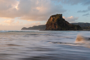 Beautiful view of Lion Rock with high tide water at Piha Beach, Auckland, New Zealand.