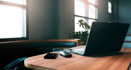 Workspace on desk with computer laptop, eyeglasses, and mobile phone decorations on wooden table