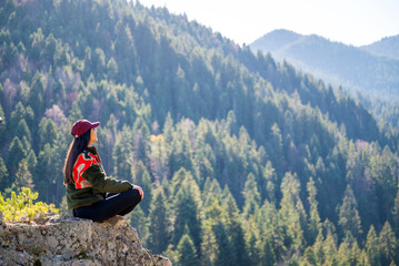 Beautiful young woman sitting on a hanging rock  in the pine mountain 