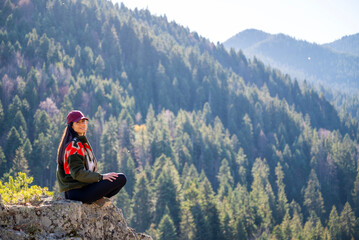 Beautiful young woman sitting on a hanging rock  in the pine mountain 