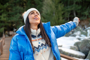Beautiful woman breathing fresh air in a snowy winter mountain