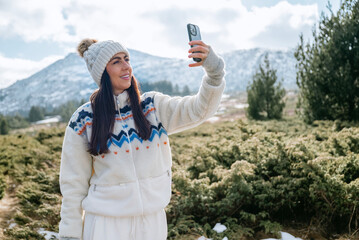 Beautiful Woman taking selfie pictures with her  phone in the Winter Mountain 