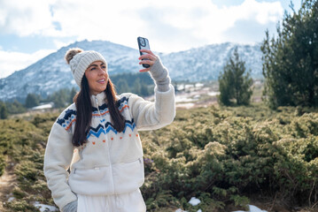 Beautiful Woman taking selfie pictures with her  phone in the Winter Mountain 