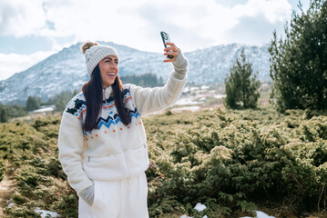 Beautiful Woman taking selfie pictures with her  phone in the Winter Mountain 