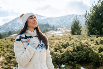 Beautiful woman breathing fresh air in a snowy winter mountain