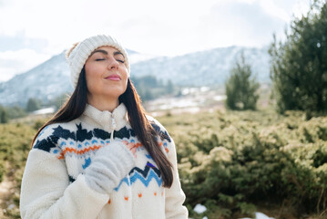 Beautiful woman breathing fresh air in a snowy winter mountain