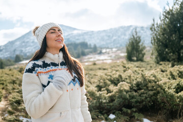 Beautiful woman breathing fresh air in a snowy winter mountain