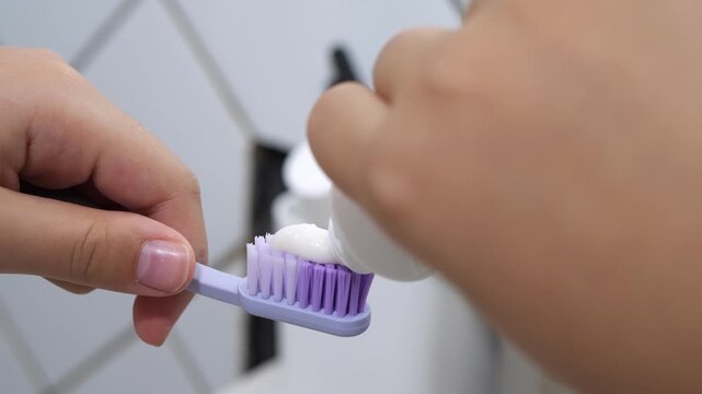 Squeezing toothpaste onto a toothbrush