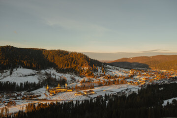 Sunlit Mountain Village Valley With SnowCapped Rooftops And Winding Road Bathed In Warm Light, PineCovered Slopes Framing