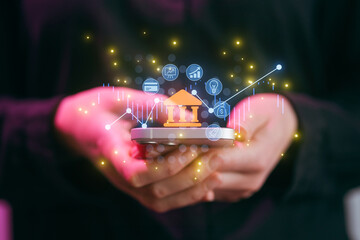 Hands hold a smartphone with digital icons showing finance data and banking information in a modern setting