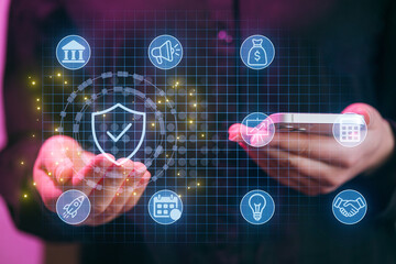 Man holds smartphone while interacting with digital security icons and symbols in a modern setting