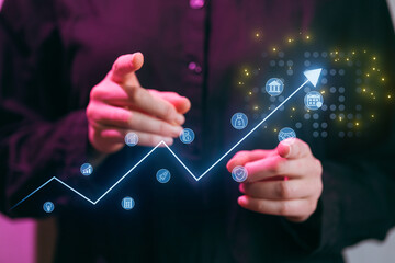 Business professional points at growth chart and icons in meeting to discuss trends and strategies for improvement