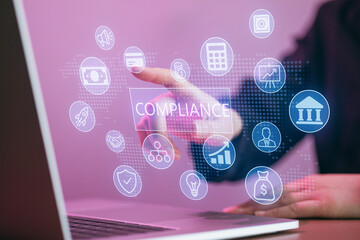 Finger touches compliance icon on digital screen with various business symbols in office setting during daytime