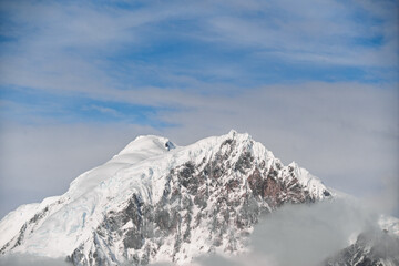 Antarctica Wilhelmina Bay Glacier Mountain Peak Covered in Powdered Snow Blue Sky Partially Clouds. Beautiful Natural Frozen Landscape Close Up
