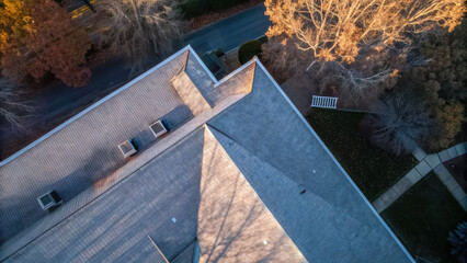 Roof with hail damage marked by inspection chalk concept. Aerial view of a rooftop surrounded by trees in autumn colors.