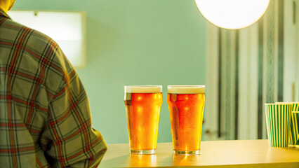 Golden beer glasses glowing on wooden table concept. Two glasses of refreshing beer on a stylish bar.