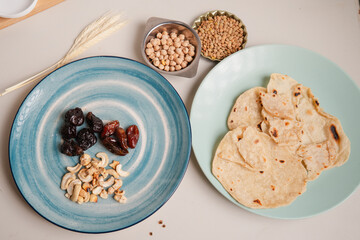 plate with dates, nuts, alongside a plate of flatbread, lentils, and chickpeas