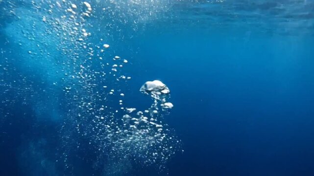 Underwater view of bubbling air ascending towards the surface in a deep blue ocean environment
