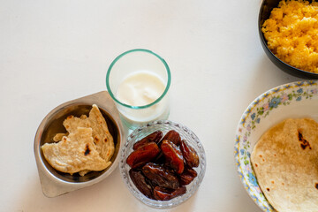Iftar during Ramadan, a glass of yogurt with a plate of dates and a plate of bread, top view