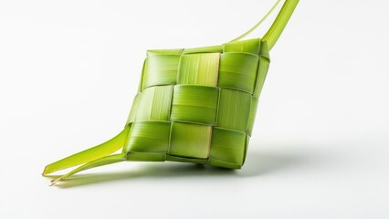This festive bright green ketupat, traditionally woven from fresh palm leaves into a geometric diamond shape, is captured in a clean studio close-up on white.