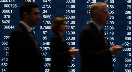 Business People Walking Past Stock Market Display