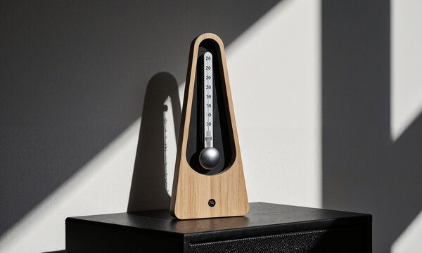 Abandoned Metronome. A classic wooden metronome sits on a speaker box, its pendulum still. Lit by a single source, casting