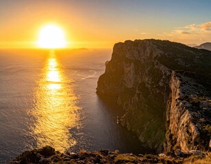 Golden sunset illuminates ocean and dramatic cliffside landscape.
