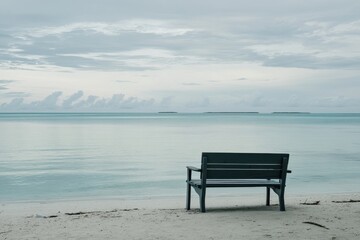 Scenic view of a calm beach with a bench facing the tranquil sea and distant islands