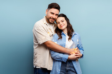 Naklejka premium Portrait of happy couple, man hugging beautiful woman looking at camera isolated on blue background