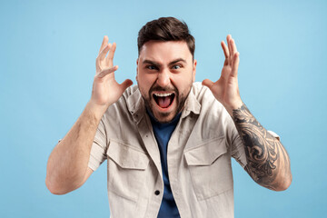 Angry, sad man screaming looking at camera isolated on blue background