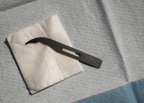 Petit scalpel utilis&eacute; par les soignants pour couper les fils, d&eacute;pos&eacute; sur une compresse blanche et un fond st&eacute;rile