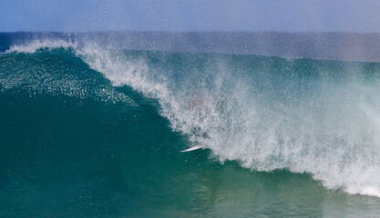 Fototapeta premium Surfer riding in the tube of a wave with just the tip of the surfboard visible