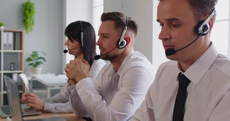 Professional operator team in a modern office listens on a headset and tracks issues on a laptop, ensuring customer service via the hotline. Team with headsets provides customer support. - Powered by Adobe