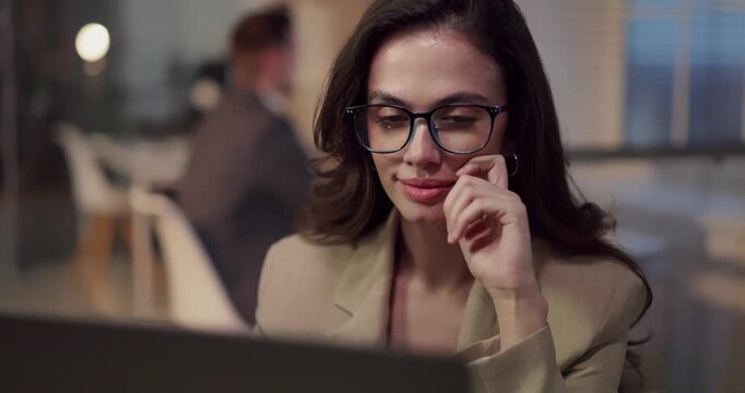 Smiling woman analyst working on laptop in office. Focused businesswoman reviews finance data and statistics, plans steps, and tracks results. Concept highlights success and productivity.