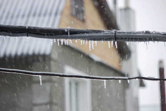 Electric power lines covered in ice and icicles after freezing rain. Winter