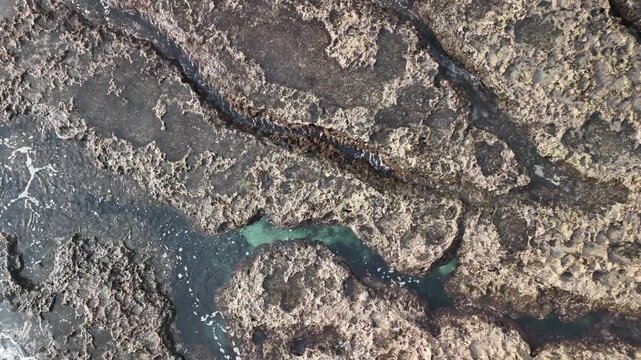 B roll of eroded coastal rock with flowing seawater revealing grooves textures and patterns that symbolize memory time harmony and tension in a poetic natural shoreline scene