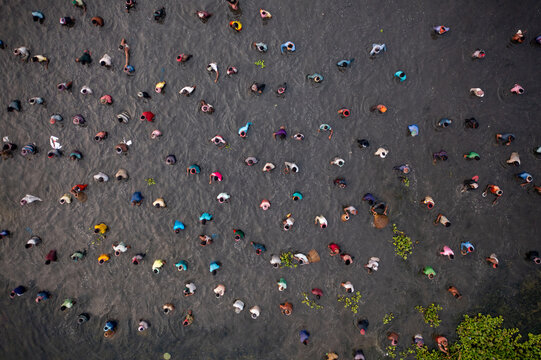 Pabna, Bangladesh - 05 December 2020: Aerial view of a river where vibrant dots of people wading through the silvery water, creating a lively mosaic under the watchful eye of the drone.