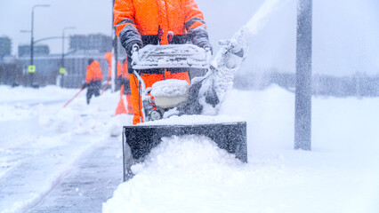 A janitor removes snow after a snowfall on the street with a snow blower