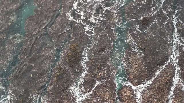 B roll of eroded coastal rock with flowing seawater revealing grooves textures and patterns that symbolize memory time harmony and tension in a poetic natural shoreline scene