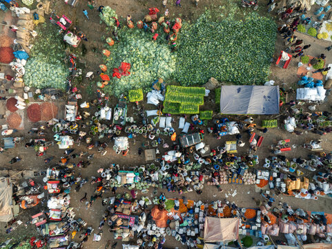 Bogura, Bangladesh - 19 December 2021: Aerial view of the bustling market, a vibrant tapestry of vendors and buyers amidst piles of watermelons, with the sun casting shadows on the lively scene.
