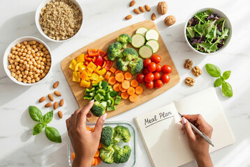 Hands Packing Healthy Lunch Box and Writing in Meal Plan Notebook